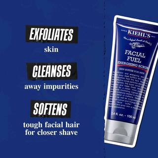 Facial Fuel Energizing Scrub tubus sotetkek hatter előtt. A szoveg jelentese: „Hamlasztja a bőrt, megtisztitja a szennyeződesektől es puhitja az erős arcszőrzetet az alaposabb borotvalkozasert.”
