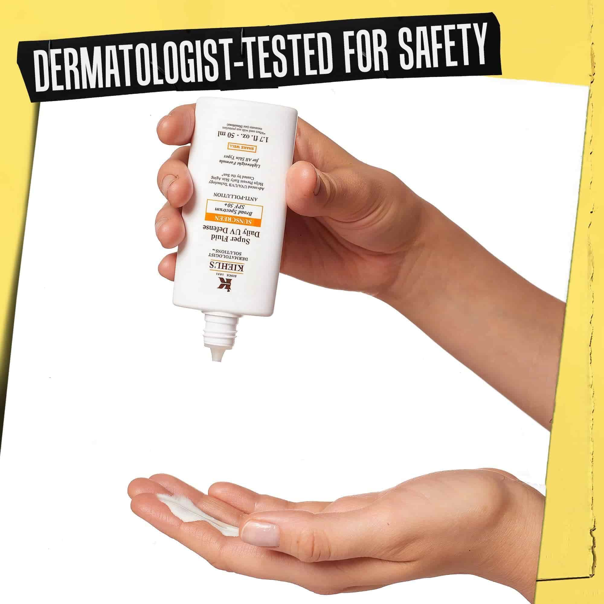 Kez, amelyre Ultra-Light Daily UV Defense-t adagolnak, a felirat: „Dermatologiailag tesztelt biztonsag”.