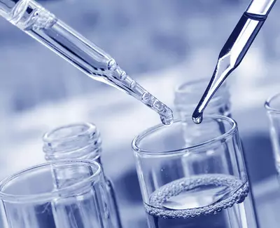 Two pipettes are positioned above a glass container filled with liquid, with droplets poised to fall into it. The image has a blue tint, creating a laboratory atmosphere.