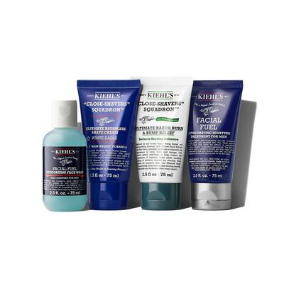 A flat lay of four Kiehl's men's skincare products, including a facial cleanser, shaving cream, after-shave balm, and hydrating moisturizer, all in vibrant blue and green packaging.