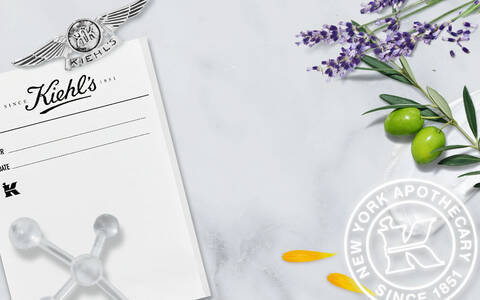 A kep egy markas hatterrel rendelkezik, amelyen levendula, olivabogyok es novenyi elemek lathatok, valamint egy regi fekete-feher fenykep a Kiehl's gyogyszerről, amely 1851 ota mukodik.