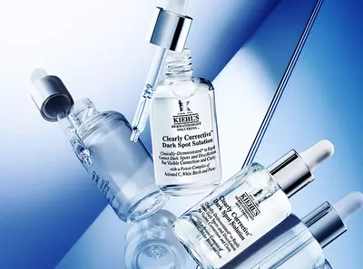 Kiehls vilagosito szerumok uveget tartalmazo kep, kek hatterrel, amely a bőrhibak kijavitasara osszpontosit.