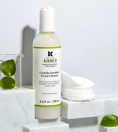 Kiehls Centella Sensitive arctisztito flakonja feher hatter előtt, pamut korongokkal es marvany feluleten.