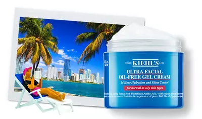 A jar of Kiehl's Ultra Facial Oil-Free Gel Cream is placed in front of a tropical scene featuring tall palm trees and a city skyline. The product emphasizes 24-hour hydration and shine control for normal to oily skin types.