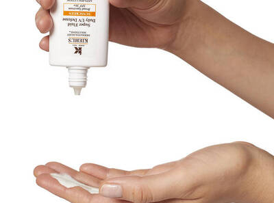 Kezben tartott Kiehl's napvedő krem, amelyet eppen a tenyerebe ontenek.