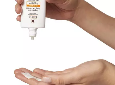 Kezben tartott Kiehl's napvedő krem, amelyet eppen a tenyerebe ontenek.