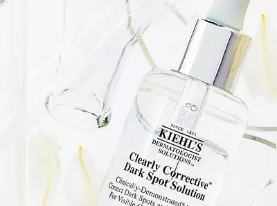 Szerum uveg, Kiehl's Clearly Corrective sotetfolt eltavolito megoldassal, feher viragokkal es atlatszo uvegekkel.