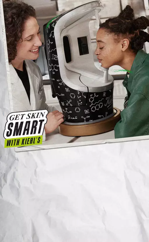 Ket fiatal, mosolygo ember egy bőrdiagnosztikai keszuleket vizsgal, mikozben a Kiehl's termekeiről beszelgetnek.